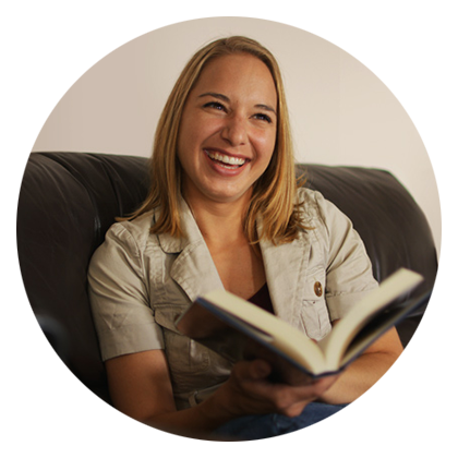 iUniverse author Julie Hockley sitting on a couch holding a book, with cheerful laughter. 